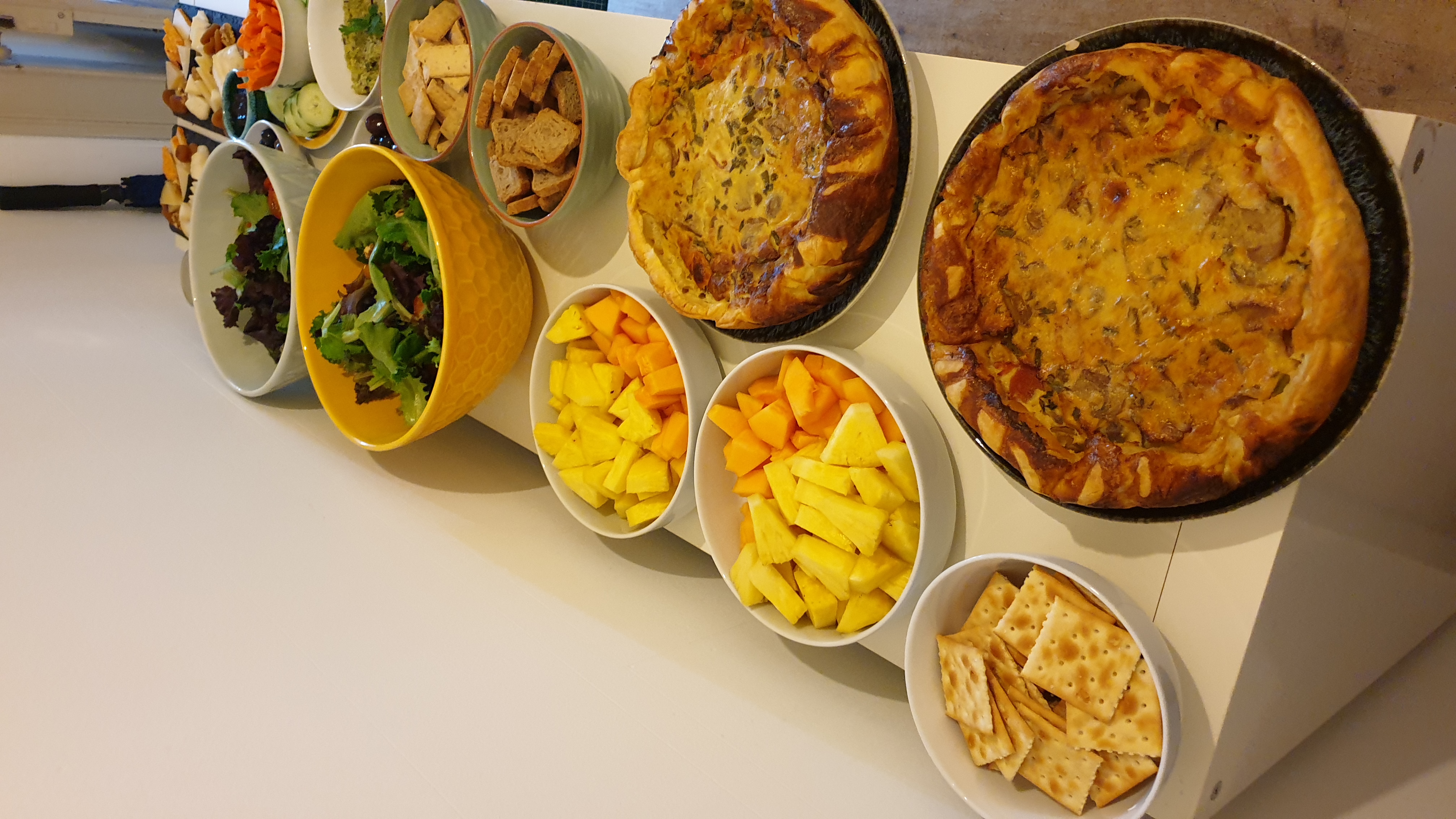 Buffet com quiches, fruta, saladas e acompanhamentos